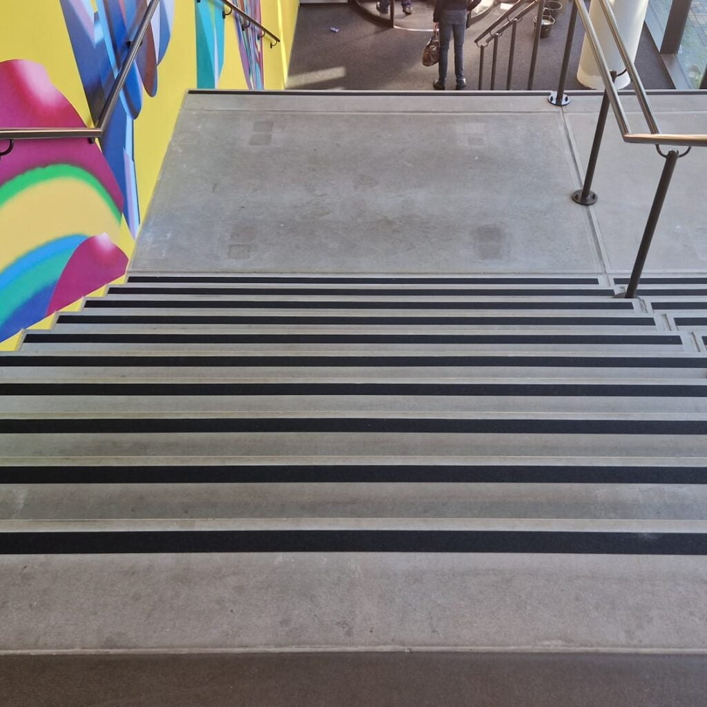 Praktijkvoorbeeld van installatie van zwarte antisliptape op traptreden. Deze trap is nu een stuk veiliger geworden.