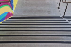 Praktijkvoorbeeld van installatie van zwarte antisliptape op traptreden. Deze trap is nu een stuk veiliger geworden.