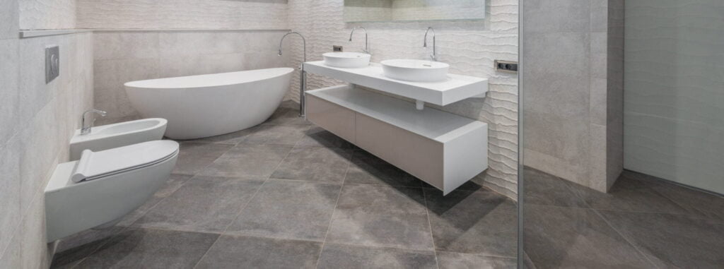 Badkamer zonder antislip oplossingen. Op de foto zijn onder andere wasbakken, een badkuip en een wc te zien.