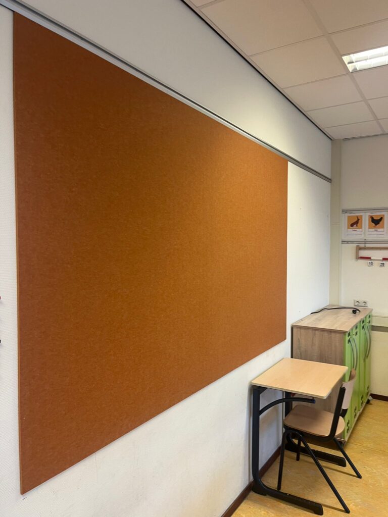 Praktijkvoorbeeld van akoestische wandbescherming bij een basisschool. Hier wordt het akoestische paneel ook gebruikt als prikbord.